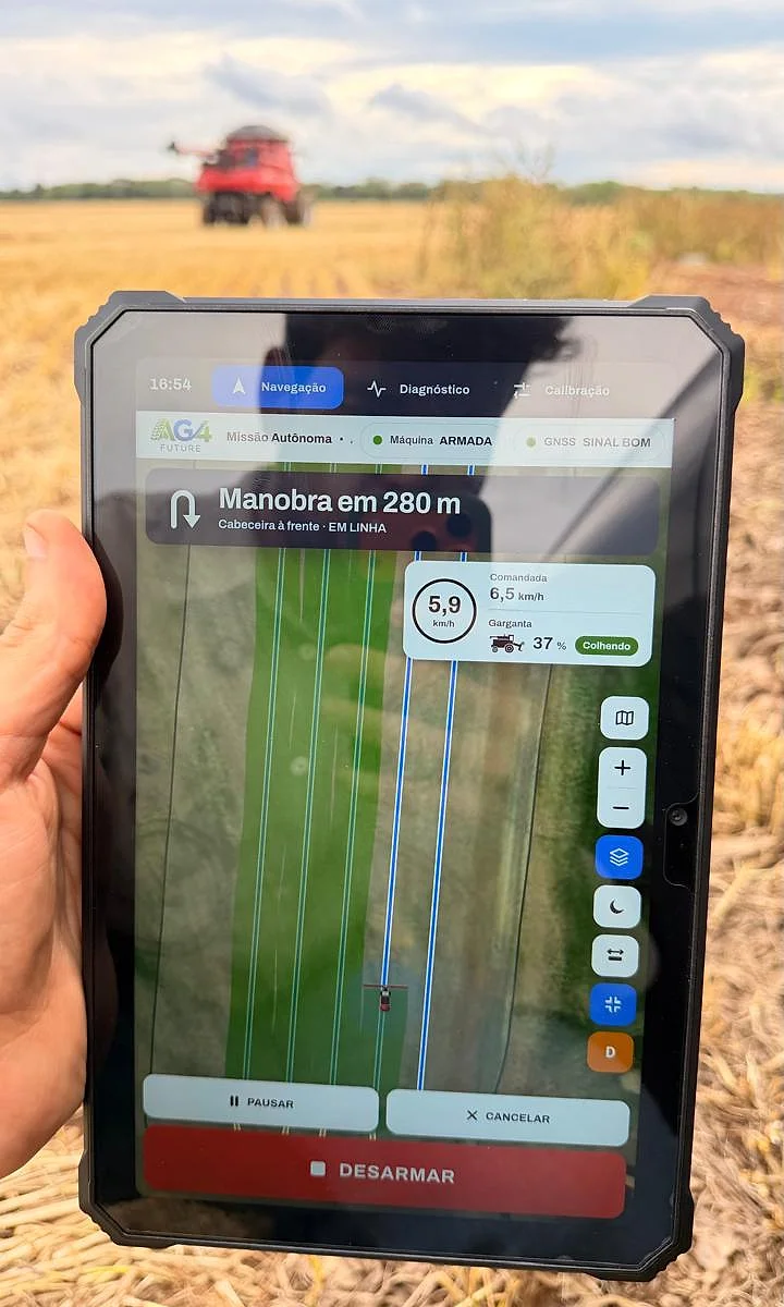 Tablet com o terminal AG4 Control em operação: máquina armada, colhendo, com manobra em 280 m; colheitadeira Case IH ao fundo